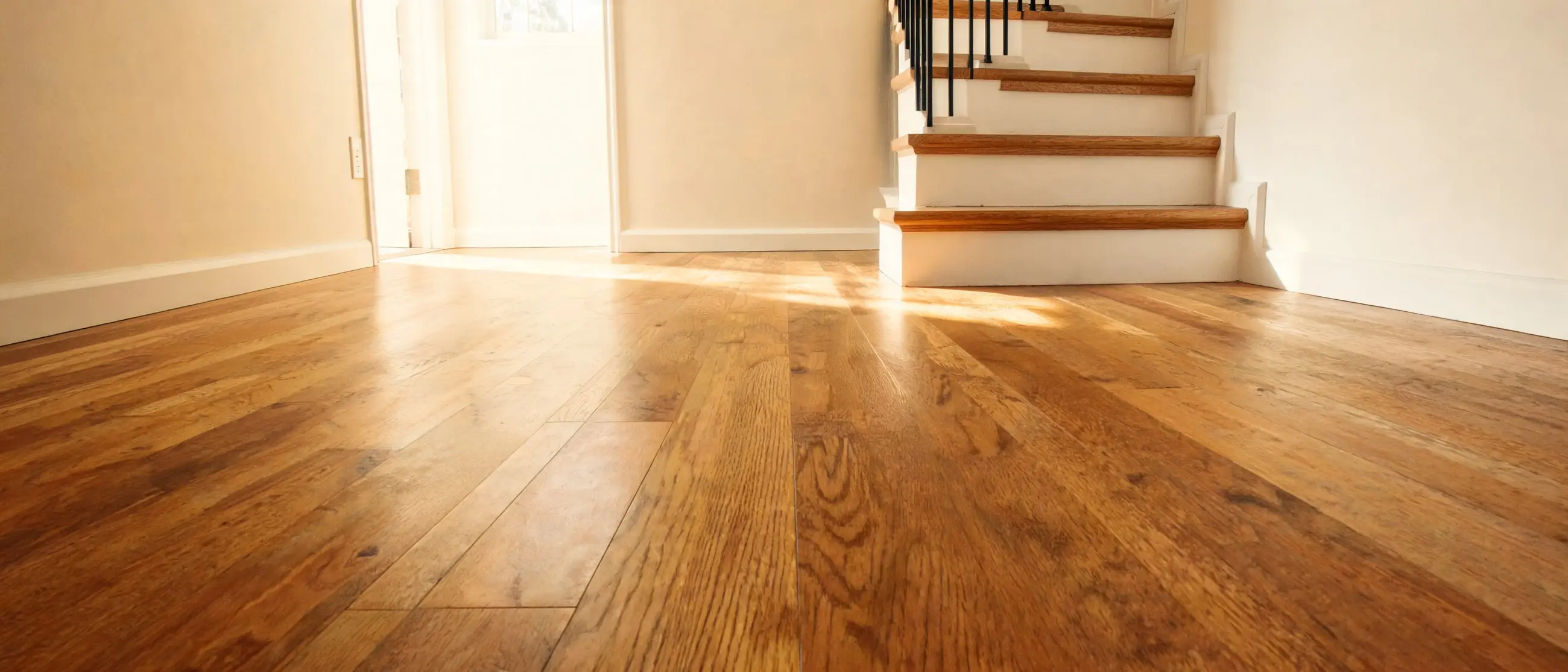 Warm oak staircase with white risers beside a refinished hardwood floor in a bright home