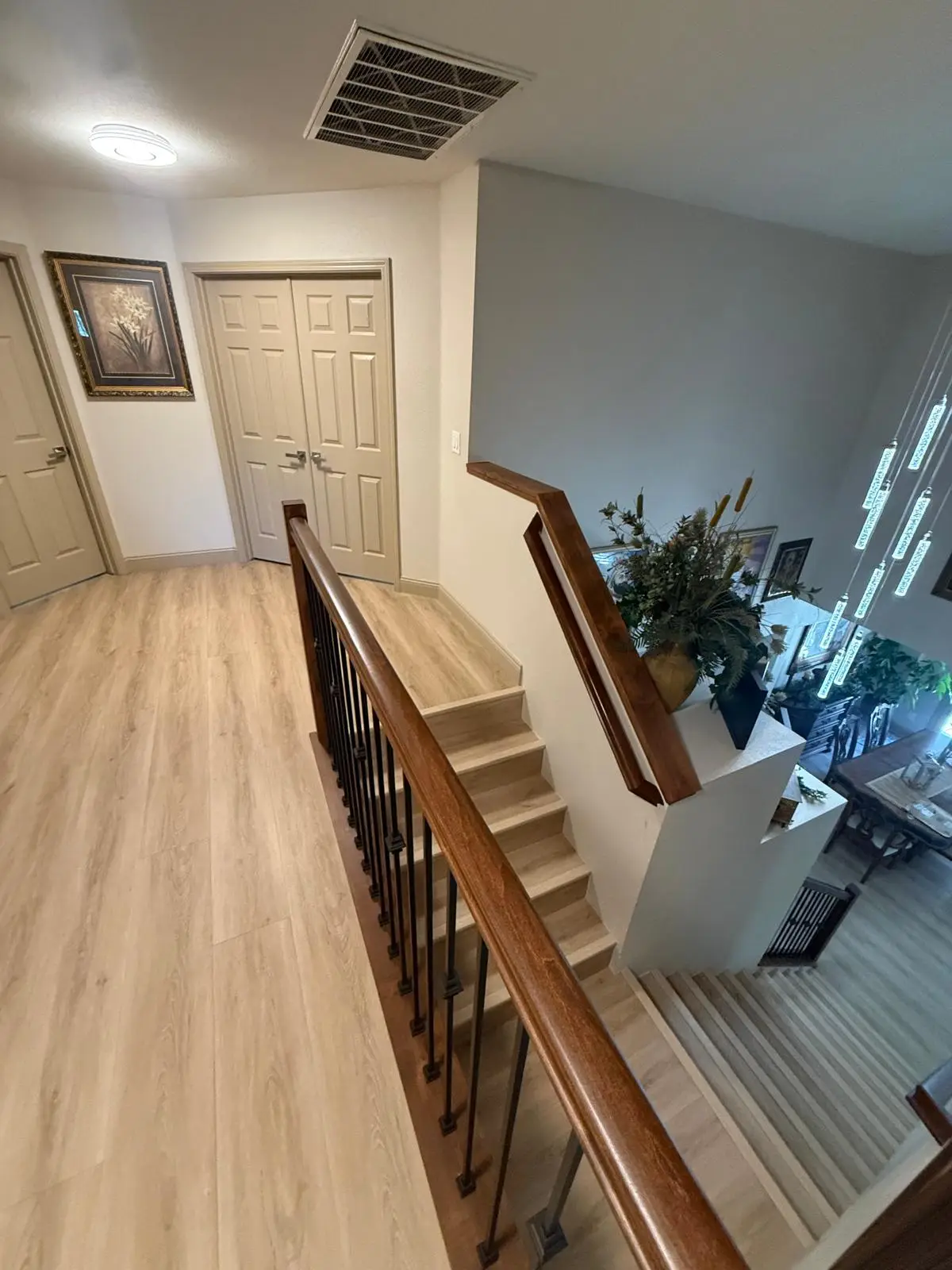 Upstairs hallway in a Sacramento home with light oak plank flooring and a new stair railing