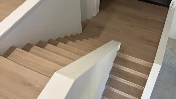 Light oak LVP stair installation with modern black metal railing in Roseville